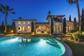 A large house with a swimming pool, a patio, and a well-maintained lawn.