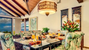 A dining area with a table set for breakfast, surrounded by upholstered chairs with a tropical print.