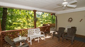 A covered porch with wooden flooring, white and gray Adirondack chairs, a small table, and a ceiling fan. - 3 Bedroom 2 bath Home, Easy Access, Covered Porch, Diligent Views & Internet (Maggie Valley)