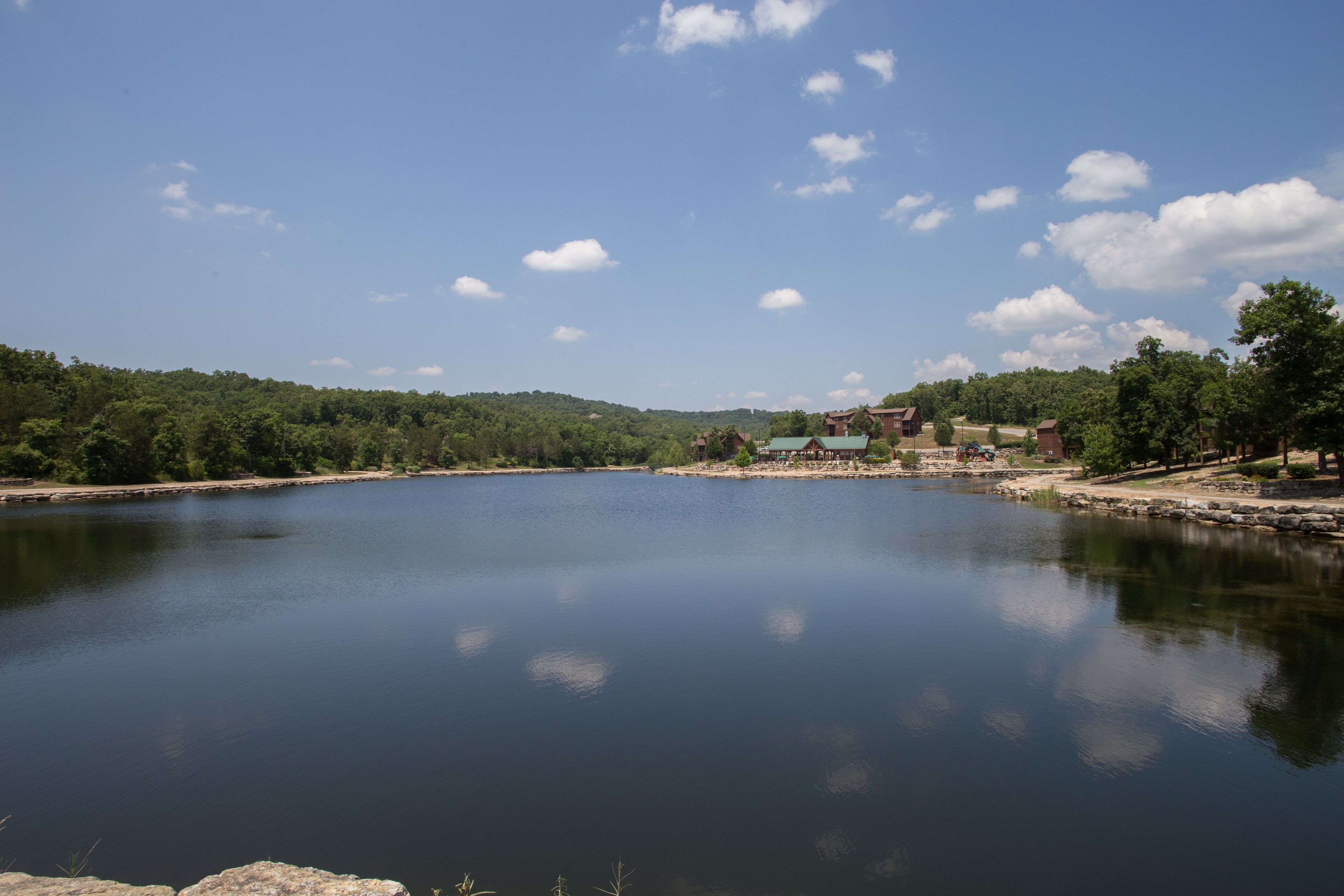 A calm lake with a small building in the distance.