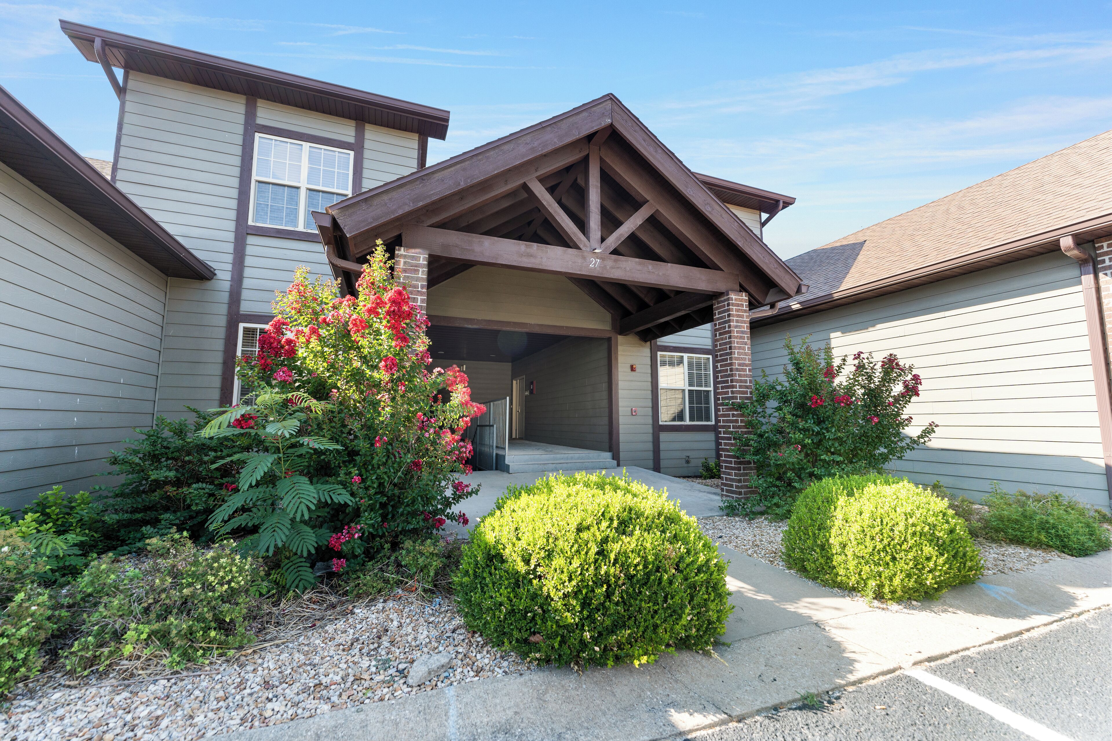 A two-story house with a covered porch, a garage, and a well-maintained garden with various plants and flowers.
