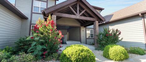 A two-story house with a covered porch, a garage, and a well-maintained garden with various plants and flowers.