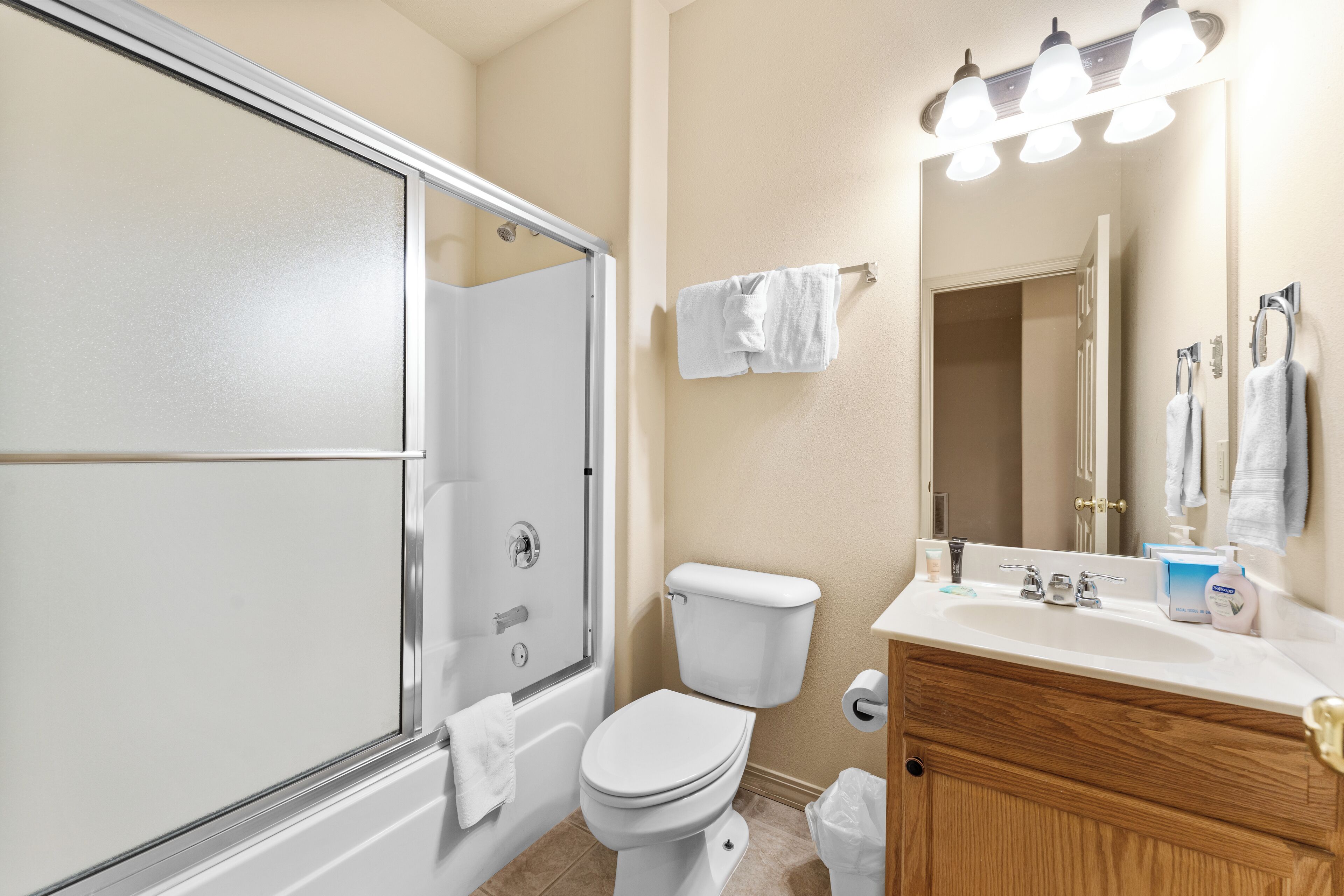 A bathroom with a glass-enclosed shower, a white toilet, a sink with a mirror, and a towel rack.