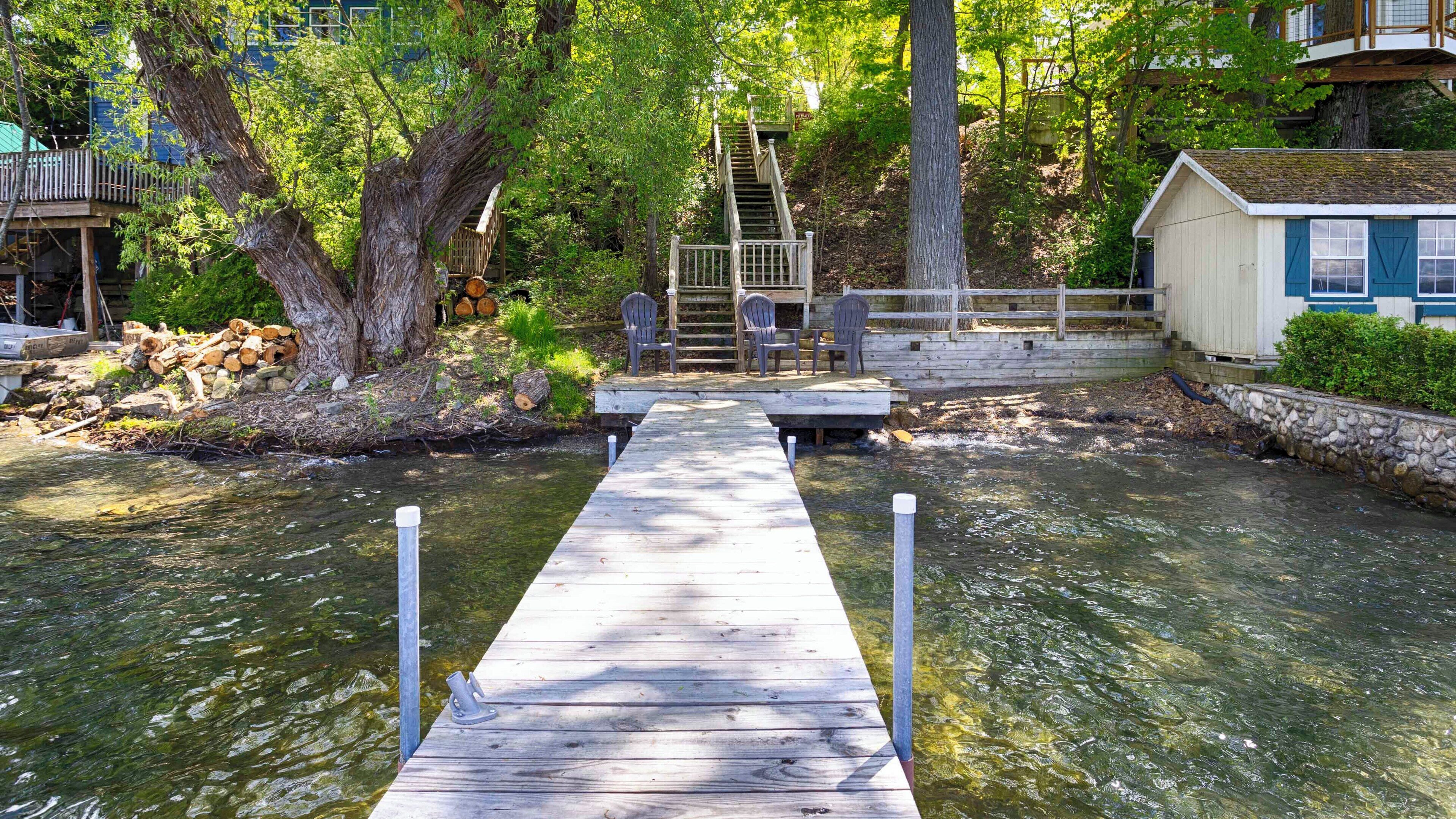Un muelle de madera que lleva a una pequeña zona con sillas y una escalera.
