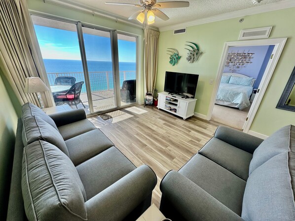Una sala de estar con balcón, televisor y cama.