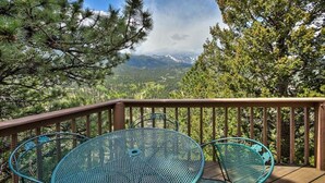Un balcon avec une table et des chaises en métal, donnant sur un paysage montagneux.