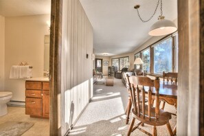 Enjoy a spacious interior with a high ceiling, large windows, and a dining area with a sofa and armchairs.