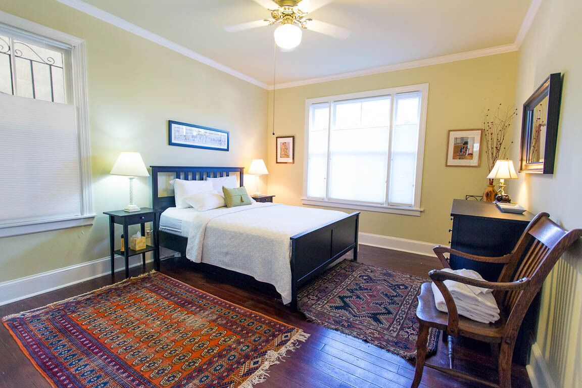 Une chambre à coucher comprenant un lit, deux tables de chevet, une chaise, un bureau et une fenêtre.