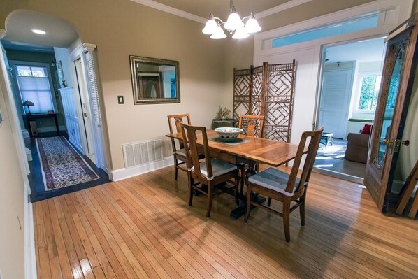A dining area with a wooden table and chairs, a decorative mirror, and a patterned partition. - Courtyard on Gaston w/ Private Living Area & Murphy Bed by Lucky Savannah (Savannah)