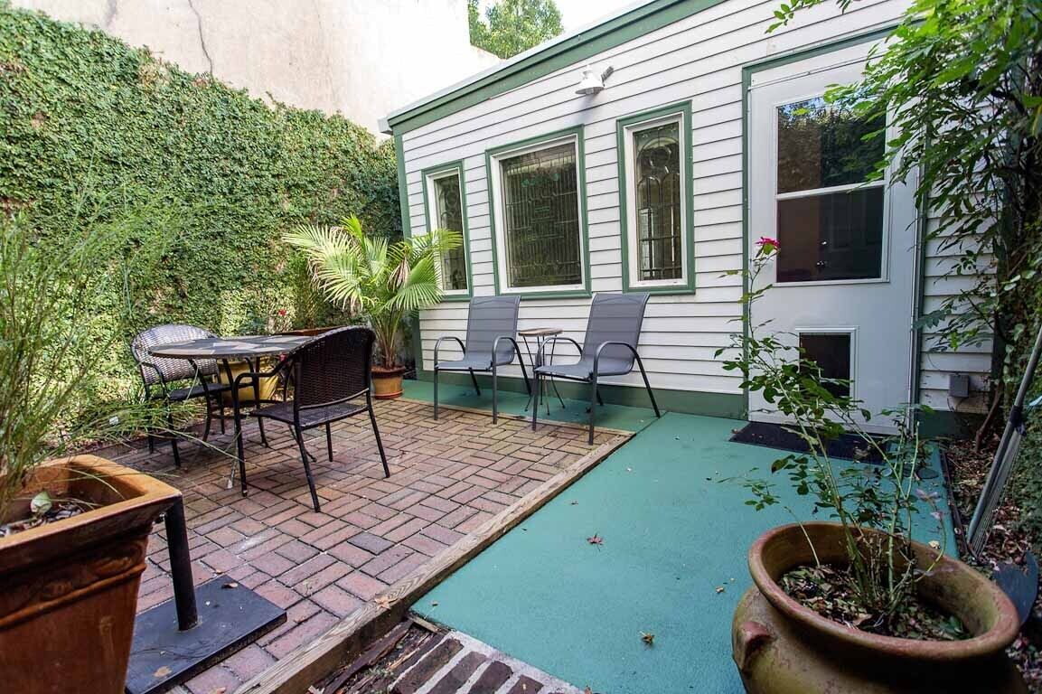 A patio with a brick floor, a table, and two chairs.