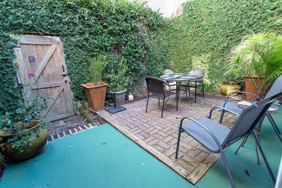 Une terrasse avec une table et des chaises, entourée d’une végétation luxuriante et agrémentée d’une porte en bois.