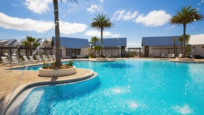 A swimming pool with lounge chairs and palm trees, surrounded by buildings with blue roofs. - Luxurious Townhouse on 30a! 6-Seat LSV, Beach, Pool, Walk to Shopping+Dining. (Panama City)
