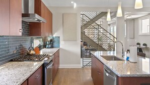 Una cocina moderna con encimeras de granito, electrodomésticos de acero inoxidable y una isla central.