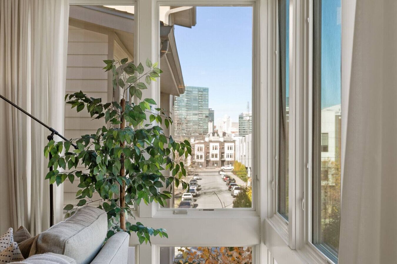 A balcony with a view of a cityscape, a potted plant, and a sofa.