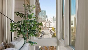 Un balcón con vistas a un paisaje urbano, una planta en maceta y un sofá.