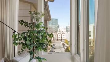 A balcony with a view of a cityscape, a potted plant, and a sofa.