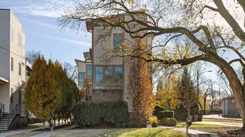 A modern two-story house with a brick facade, large windows, and a well-maintained lawn.