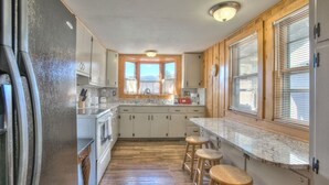 Eine Küche mit Holzausstattung, einer Granit-Arbeitsplatte und einem Fenster mit Jalousien.