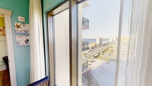 Una habitación con un ventanal grande que da a una calle y una masa de agua.