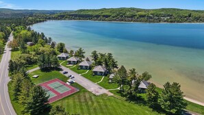 Une propriété située au bord d’un lac, comprenant plusieurs maisons, un court de tennis et une route.