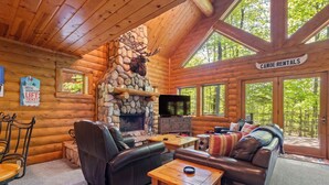 L’intérieur d’une cabane en rondins, avec une cheminée en pierre, des meubles en cuir et un panneau indiquant un service de location de canoës.