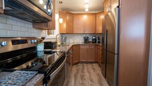 Une cuisine moderne dotée d’appareils électroménagers en acier inoxydable, de meubles en bois et d’un revêtement mural en carreaux.