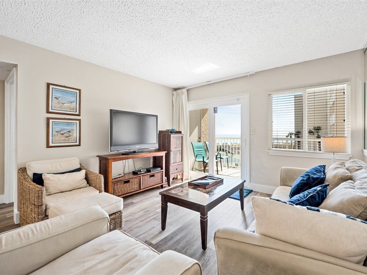 A living room with a television, wicker furniture, a wooden coffee table, and a view of the outdoors.