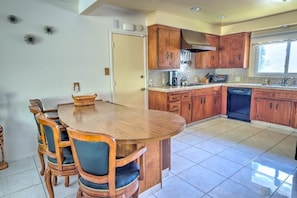 A kitchen with wooden cabinets, a dining table with chairs, and a dishwasher.