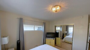 A hotel room with a bed, a television, a mirror, and a ceiling light fixture.
