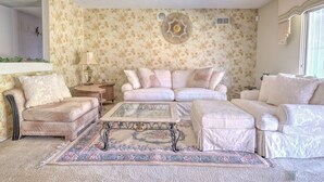 A living room with a floral wallpaper, a sofa set, a coffee table, and a rug.