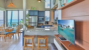 A modern kitchen with a large island, bar stools, and a TV.