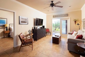 A living room with a ceiling fan, a television, a fireplace, a sofa, a coffee table, and a sign that reads 'PARKER RIVER HOUSE.'