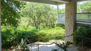 Ein überdachter Außenbereich mit einer Steinpfeiler, einem Metallgeländer und Treppen, die zu einem Balkon führen.