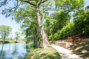 A serene lakeside park with a picnic table and a concrete pathway.