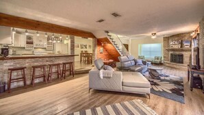 A spacious living area with a kitchen, a staircase, and a fireplace. - LD 1683 Texas River Haus (New Braunfels)
