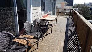 A deck with outdoor furniture, including a table and chairs, and a railing. - The Wright Spot.  A 1 bedroom with loft in the Heart of Wrightsville Beach! (Wrighsville Beach)