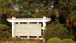 A welcome sign for Wrightsville Beach with a pergola structure and surrounding greenery. - The Wright Spot.  A 1 bedroom with loft in the Heart of Wrightsville Beach! (Wrighsville Beach)
