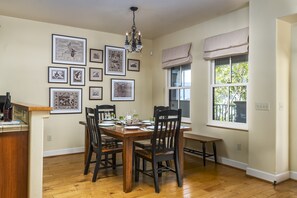 A dining area with a wooden table, black chairs, and framed artwork on the walls. - Upscale Living in Downtown Avila Beach (Avila Beach)