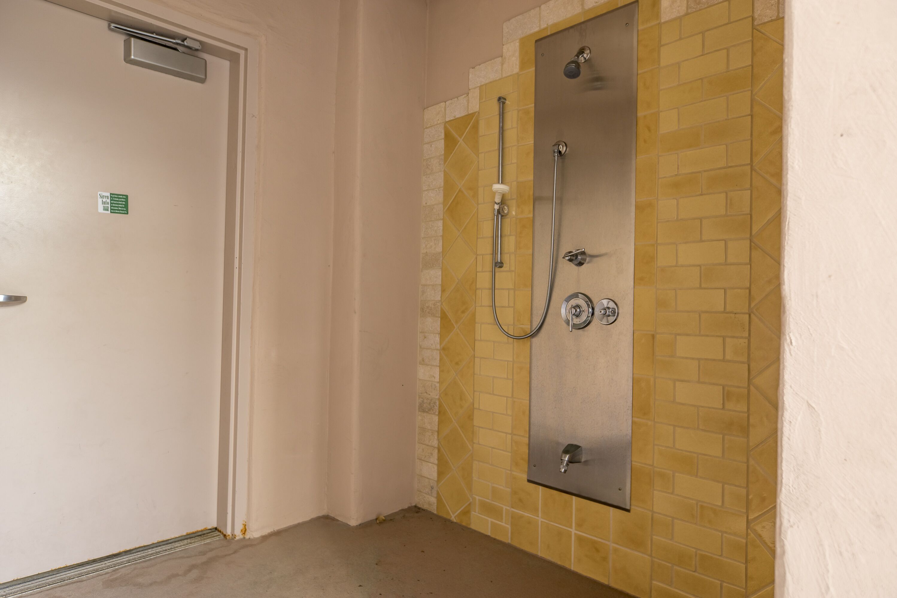 Un baño con cabina de ducha, una puerta y un revestimiento de azulejos.