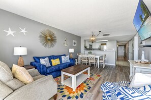 A living room with a blue sofa, a wooden coffee table, and a colorful rug. - Recently Renovated Oceanfront condo at great resort +Free Attraction Tickets! (North Myrtle Beach)