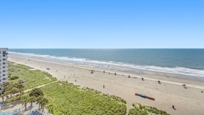 Una playa con vista despejada al océano, una orilla arenosa y un edificio al fondo.