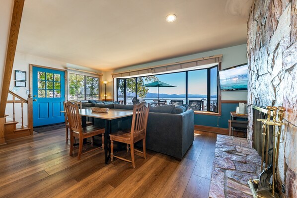A modern kitchen with a dining area, large windows, and a stone fireplace.