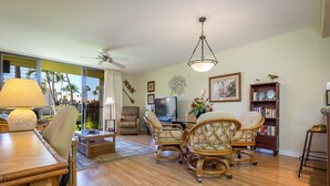 A spacious living room with a dining area, a television, and a bookshelf.