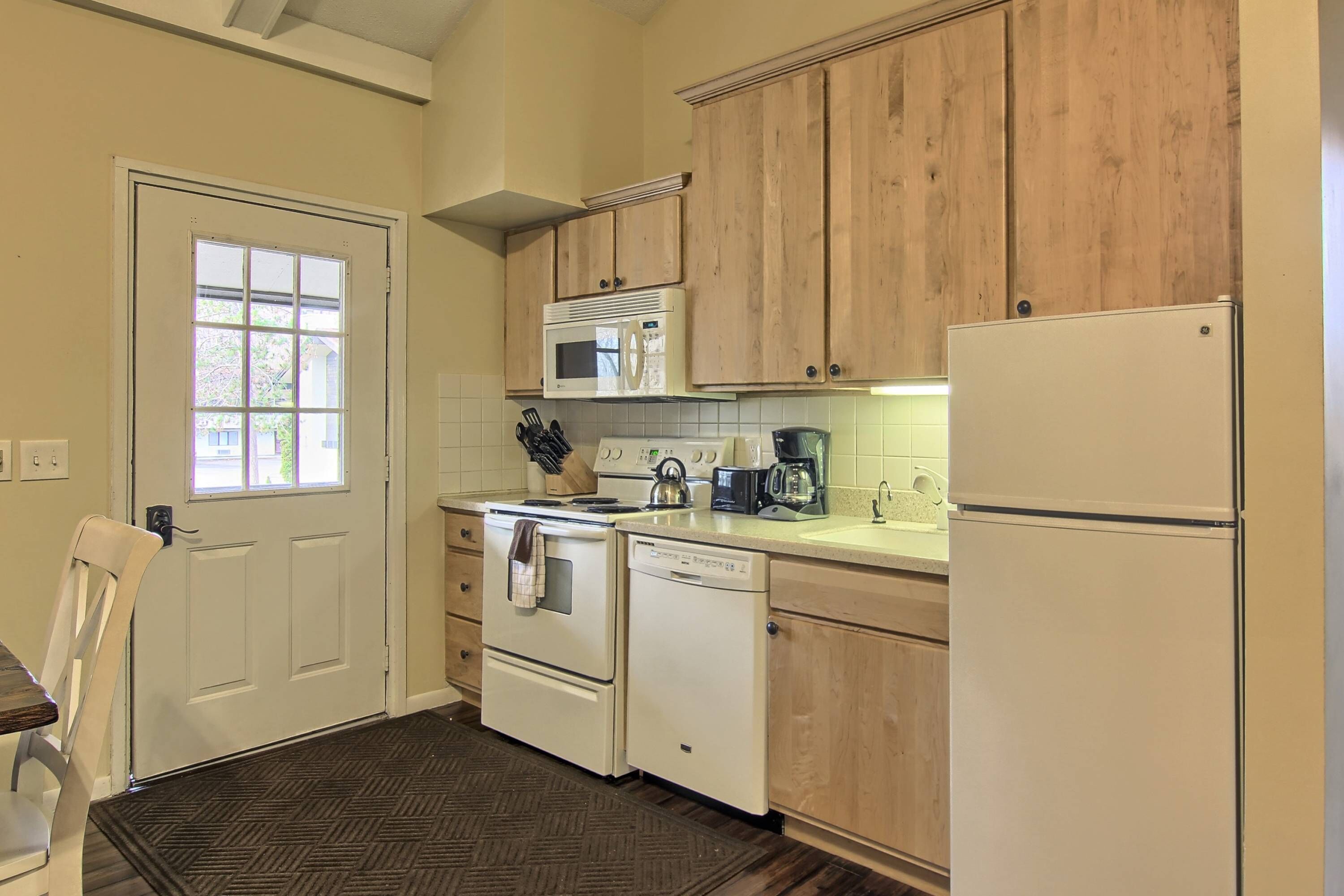 A kitchen with wooden cabinets, a white refrigerator, a microwave, a stove, and a dishwasher.