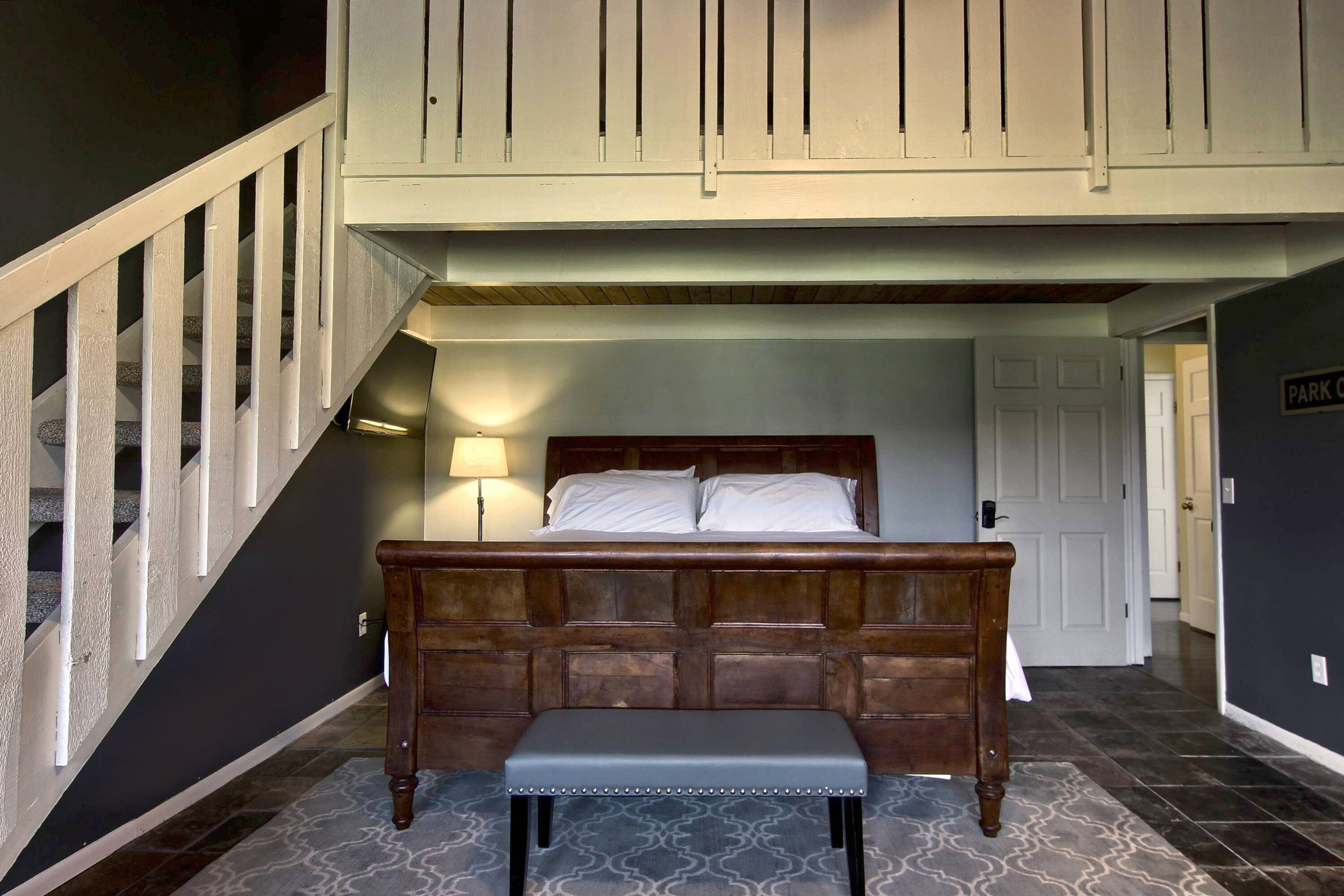 Un dormitorio con una cama de madera, un banco, una escalera y una puerta con la etiqueta 'PARK'.