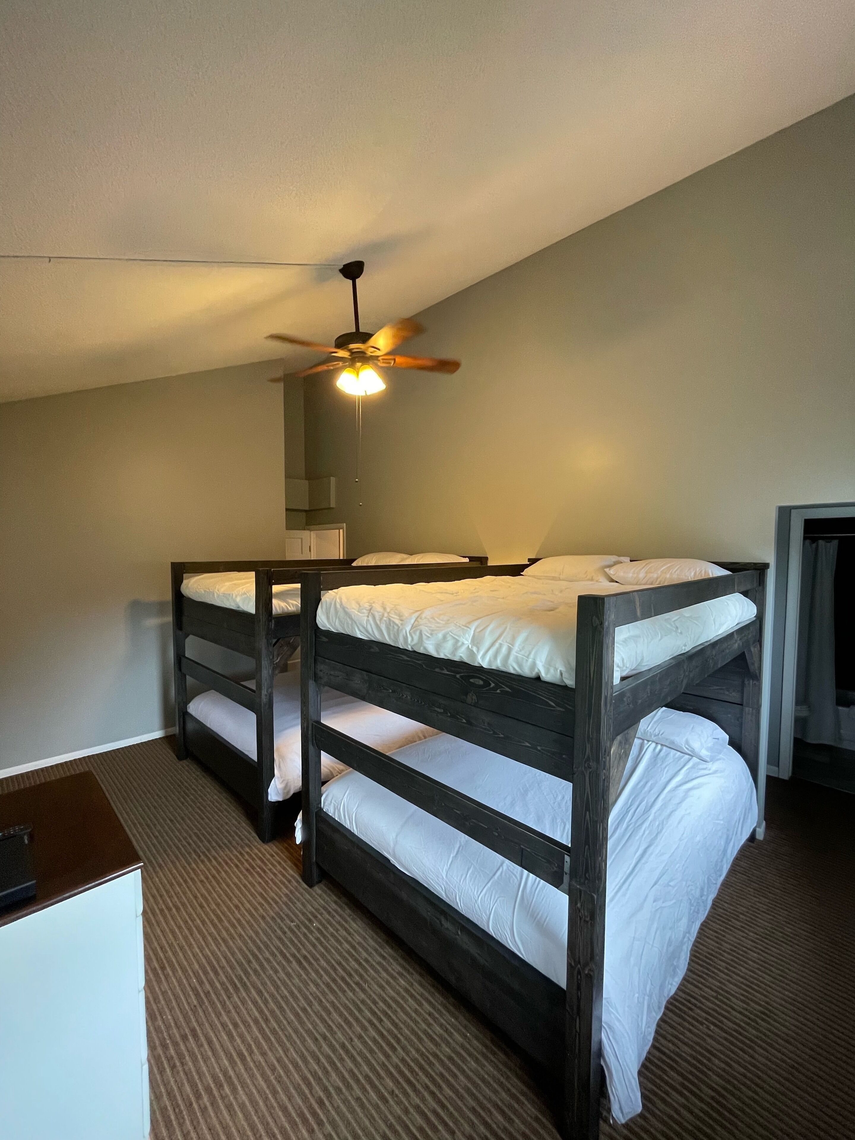 A bunk bed room with a ceiling fan and a small table.