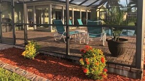 Ein überdachter Patio-Bereich mit Glasverkleidung, Sitzgelegenheiten im Freien und einem kleinen Pool.