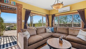 A living room with a sectional sofa, a round coffee table, and large windows offering a view of the desert landscape.