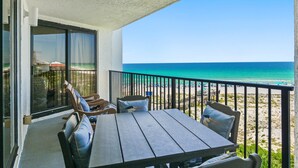 A balcony with a table and chairs, overlooking a beach with a clear view of the ocean. - Beach Front Balcony ~ Seasonally Heated Pool (Miramar Beach)