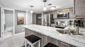 A modern kitchen with a large island, stainless steel appliances, and a view of the beach through the window. - 620- Time for a trip to the Beach? Rustic, Coastal Beachfront Retreat (Destin)